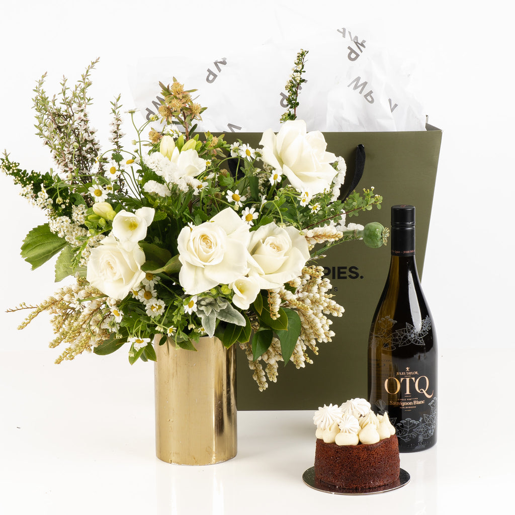 "A Special Moment Gift" featuring a fresh white posy, a bottle of Jules Taylor OTQ Sauvignon Blanc, and a decadent red velvet cake. Presented in a premium Wild Poppies gift bag with satin ribbon and tissue paper, this elegant gift set is perfect for celebrating birthdays, anniversaries, or any memorable occasion with a blend of beauty, indulgence, and luxury.