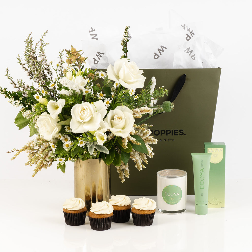 "French Pear and Petal Gift Set" featuring a fresh white and green posy, Ecoya French Pear scented candle, and hand cream. Optionally paired with four delicate Petal cupcakes. Presented in a premium Wild Poppies gift bag with satin ribbon, this elegant set blends fresh florals with soothing, fruity aromas for a perfect indulgence.