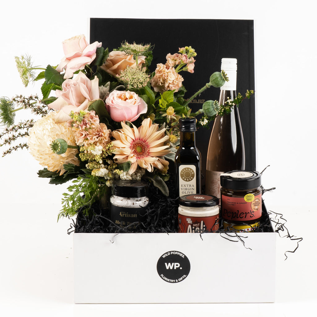 "New Home Gift Hamper" featuring a fresh pastel posy, Kiwi Artisan black truffle sea salt, Jules Taylor The Jules Rosé, Village Press extra virgin olive oil, Wise Boys garlic aioli, and Pepler's tamarillo and ginger chutney. Elegantly presented in a premium Wild Poppies gift box with tissue paper and satin ribbon, a perfect housewarming gift to celebrate new beginnings.