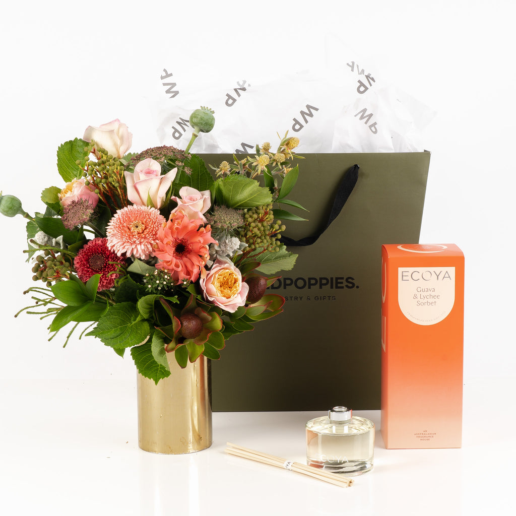 "Petals & Guava Diffuser Gift Set" featuring a vibrant pink, orange, and green posy alongside Ecoya’s Guava & Lychee Sorbet diffuser. Presented in a gorgeous Wild Poppies gift bag with tissue paper and satin ribbon, this set adds a burst of color and refreshing tropical fragrance to any space. Perfect for gifting or indulging yourself.