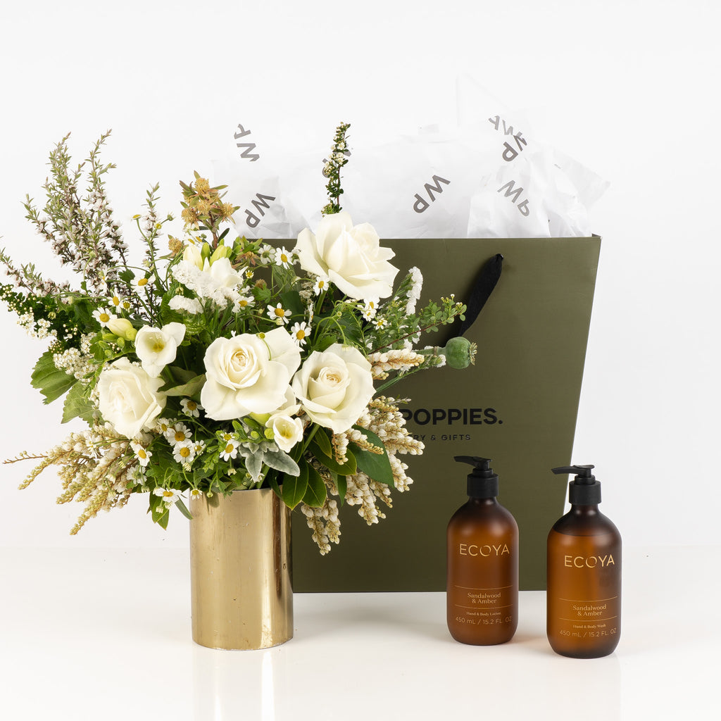 "Sandalwood & Amber Bloom Gift" featuring a fresh white and green posy, Ecoya Sandalwood and Amber hand and body lotion, and hand and body wash. Presented in a premium Wild Poppies gift bag with tissue paper and satin ribbon, offering a luxurious, spa-like experience that combines natural elegance and soothing self-care.