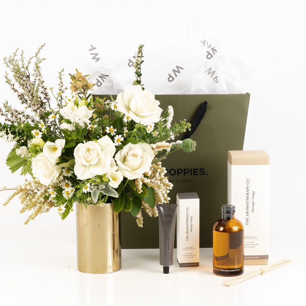 "Ultimate Self Care Gift Set" featuring a fresh white and green posy, The Aromatherapy Co. Sandalwood and Cedar hand cream, and reed diffuser. Presented in a premium Wild Poppies gift bag with satin ribbon and tissue paper, this luxurious set is perfect for creating a moment of relaxation and indulgence with calming, grounding scents and fresh florals.